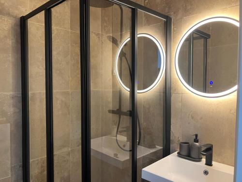 a bathroom with a sink and a shower with two mirrors at Maison le Bac Paris Aparthotel in Paris