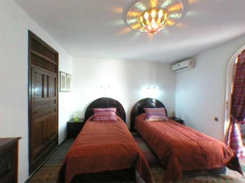 a bedroom with two beds and a chandelier at Dar El Mouhit in Sale