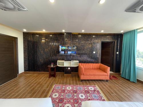 a living room with a couch and a tv on a wall at Hamdan Hotel and Resort in Murree