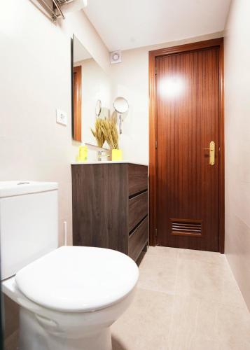 a bathroom with a toilet and a wooden door at Summerlandrota Veracruz28 in Rota