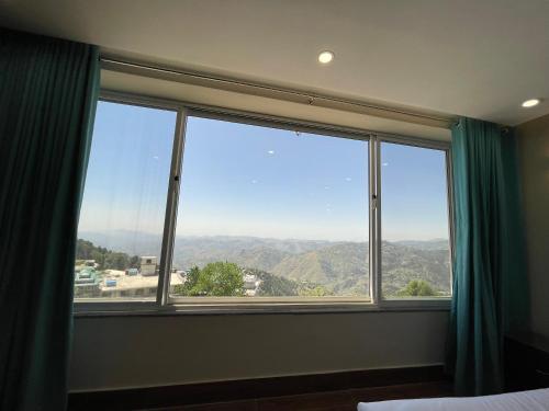 a large window with a view of the mountains at Hamdan Hotel and Resort in Murree