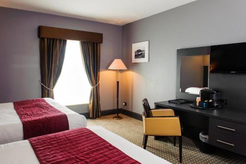 a hotel room with two beds and a desk at Cliffs of Moher Hotel in Liscannor