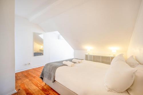 um quarto branco com uma cama grande e almofadas brancas em GuestReady - B-MAD Museum At Your Doorstep em Lisboa