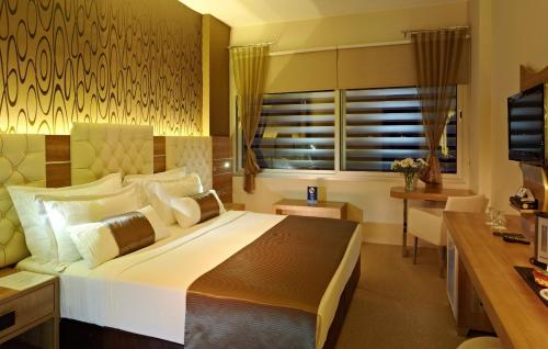 a bedroom with a large bed and a desk at Orty Airport Hotel in Izmir