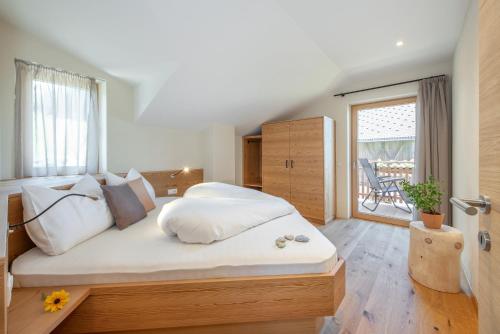 una camera da letto con un grande letto con lenzuola bianche di Furnerhof Apt Olpenglühn a Collepietra