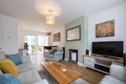 een woonkamer met een bank en een flatscreen-tv bij GuestReady - Tranquil Retreat near Bramall Hall in Cheadle