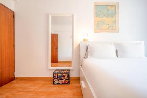 a bedroom with a white bed and a mirror at GuestReady - Salty Retreat in Trafaria in Costa da Caparica