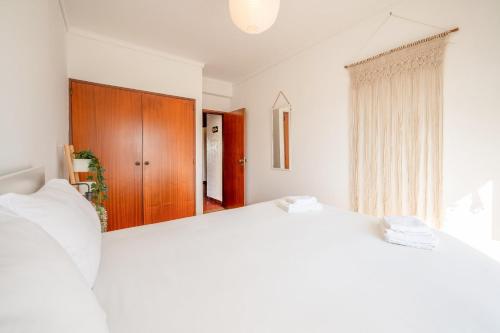 a bedroom with two white beds and a wooden door at GuestReady - Salty Retreat in Trafaria in Costa da Caparica