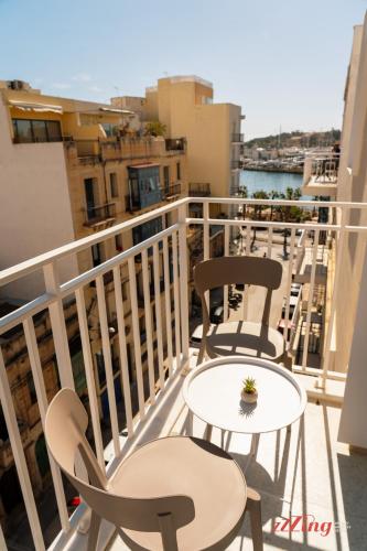a balcony with two chairs and a table at Stuart Rooms by Zzzing in Il-Gżira