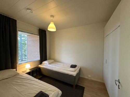 a bedroom with two twin beds and a window at Kotimaailma - Uusi rivitalokolmio saunalla # 3 in Kokkola