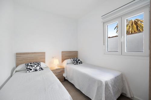Dos camas en una habitación con ventana. en Joal Piscina Privada, en Chiclana de la Frontera