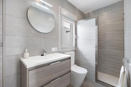 Un baño con lavabo, inodoro y espejo. en Joal Piscina Privada, en Chiclana de la Frontera