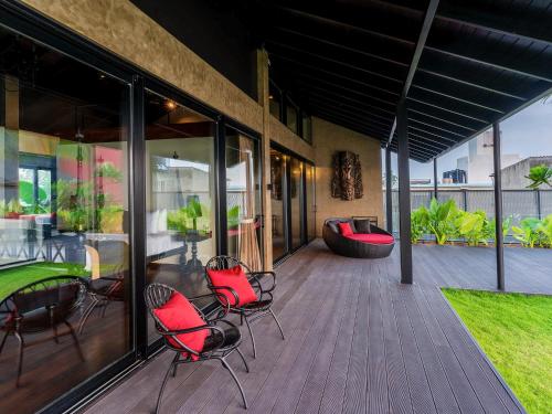 a patio with red chairs and a table on a deck at DORMERO Hotel Sri Lanka Hikkaduwa Beach in Hikkaduwa