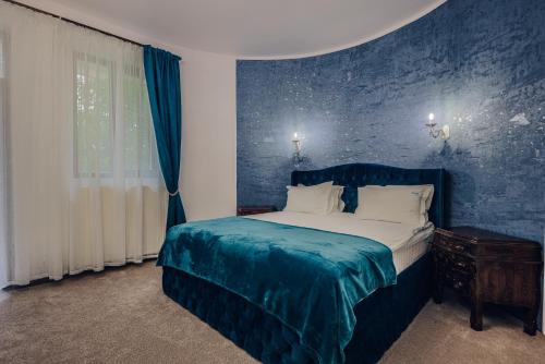 a blue bedroom with a bed with a blue wall at Villa Tom in Sinaia