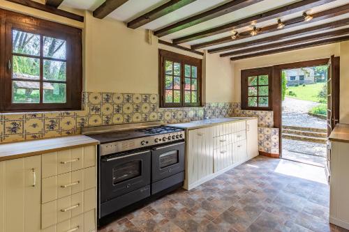 Il comprend une cuisine équipée d'un four avec plaques de cuisson noires. dans l'établissement Les Chenes, avec piscine, tennis et lac privatif, à Guerquesalles