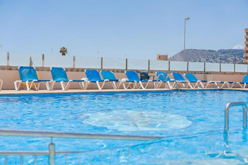uma fila de cadeiras azuis numa piscina em Port Europa em Calpe