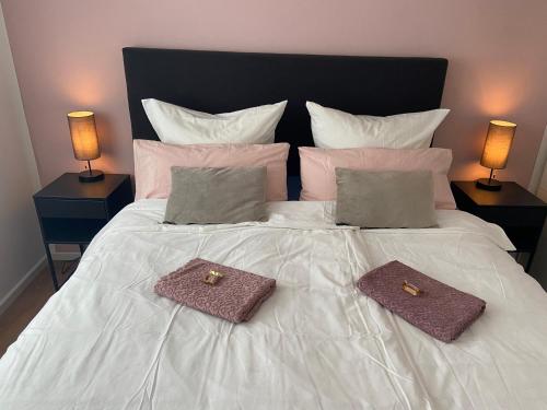 a white bed with two towels on it with two lamps at MiCasa OL - Deluxe Apartment mit Stil - Carport Stellplatz - Küche - WLAN - 3,7 KW Steckdose für E Auto - Terrasse in Oldenburg