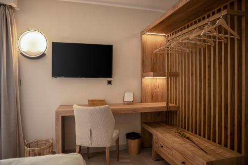 a bedroom with a desk with a television and a chair at Chrissida Hotel in Nea Kydonia