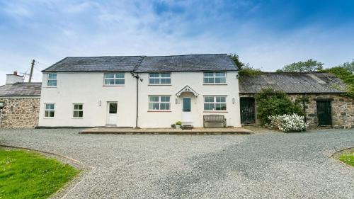 a large white house with a gravel driveway at Ty Poeth in Brynsiencyn