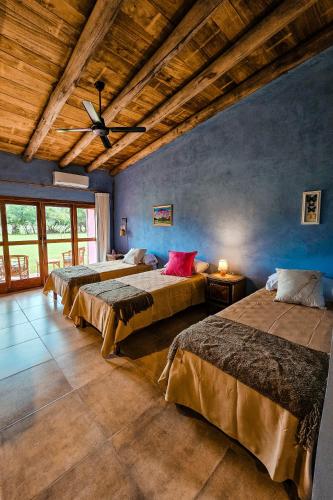 a bedroom with three beds and a ceiling fan at Posada Mbarete in San Miguel
