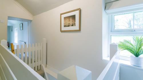 a white room with a crib and a picture on the wall at Ty Poeth in Brynsiencyn