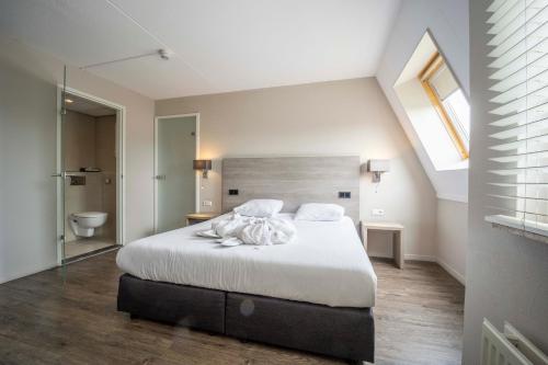 a bedroom with a large bed and a bathroom at Fletcher Zuiderduin Beachhotel in Westkapelle