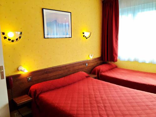 オルレアンにあるホテル サン テニャンのベッド2台と窓が備わるホテルルームです。
