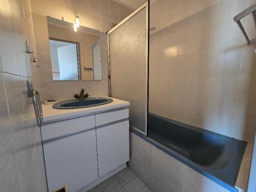 une salle de bain avec un lavabo, un miroir et une baignoire dans l'établissement Vue sur la mer, à Valras-Plage