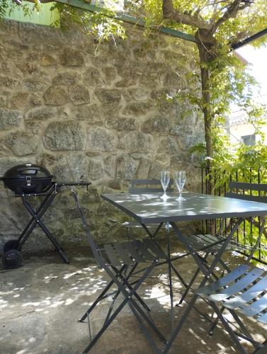 une table de pique-nique avec deux verres à vin et un grill dans l'établissement Sorène - Une maisonnette en Cévennes, à Sainte-Marguerite-Lafigère