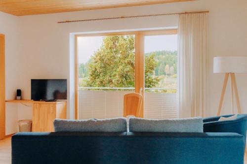 a living room with a blue couch and a large window at Lindenhaus in Zwiesel