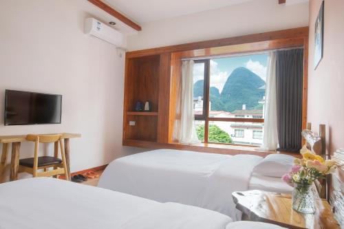 Habitación de hotel con 2 camas y ventana en Yangshuo Xiao Long River Hotel, en Yangshuo