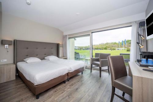 a bedroom with a bed and a desk with a computer at Fletcher Zuiderduin Beachhotel in Westkapelle