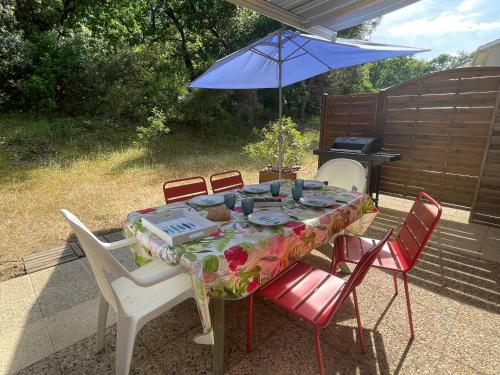 - une table avec des chaises, un parasol et un grill dans l'établissement Rêves d'Océan villa familiale calme bord de mer piscine partagée surf, à Soulac-sur-Mer