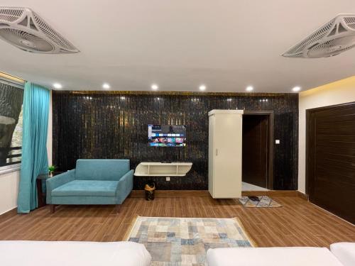 a living room with a blue chair and a sink at Hamdan Hotel and Resort in Murree