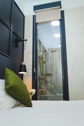 a bed with a green pillow and a window at Dondar Hotel Formula 1 View in Baku