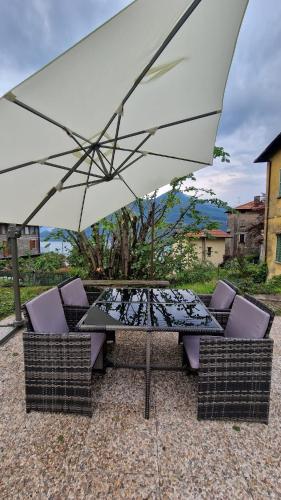 a table and chairs under a white umbrella at villetta con giardino privato in Cremia