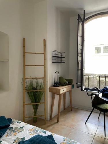 une chambre avec un lit, un bureau et une fenêtre dans l'établissement T1 arlésien au coeur du centre-ville, à Arles
