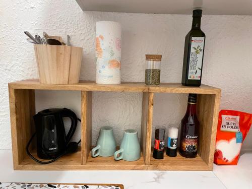 une étagère en bois avec une bouteille de vin et des tasses dans l'établissement T1 arlésien au coeur du centre-ville, à Arles