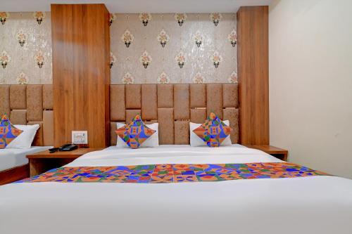a bedroom with a large white bed with colorful pillows at FabExpress SK Prime in Ujjain