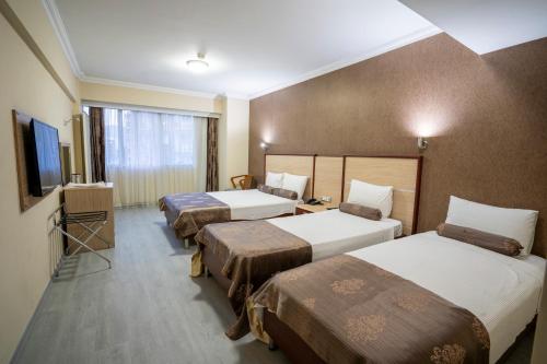 um quarto de hotel com três camas e uma televisão de ecrã plano em HALLEY OTEL em Denizli