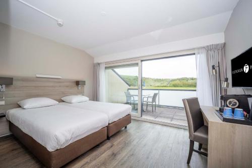 a hotel room with a bed and a balcony at Fletcher Zuiderduin Beachhotel in Westkapelle