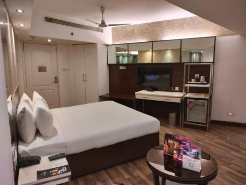 a bedroom with a bed and a table and a kitchen at Regenta Place Bangalore, Cunningham Road in Bengaluru