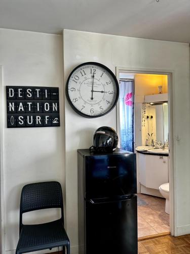 La salle de bains est pourvue d'une horloge murale et d'une chaise. dans l'établissement Sweet Home Montrouge, à Montrouge