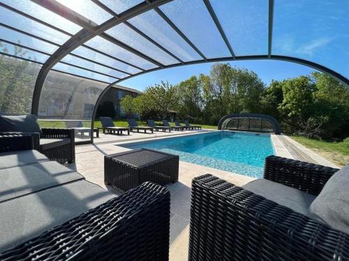 - une piscine avec des chaises et une pergola à côté de la piscine dans l'établissement La Millière - Piscine & campagne - Bonchamps, à Le Poiré-sur-Vie