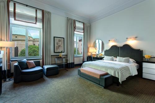 ein Schlafzimmer mit einem Bett, einem Stuhl und einem Spiegel in der Unterkunft Rocco Forte Hotel De Rome in Berlin