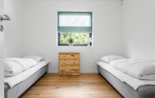 two beds in a white room with a window at 4 Bedroom Lovely Home In Væggerløse in Marielyst