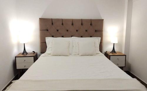 1 dormitorio con 1 cama blanca grande y 2 lámparas en APARTAMENTOS COMPLETOS Cama Queen a 10 min Aeropuerto Lima Per, en Lima