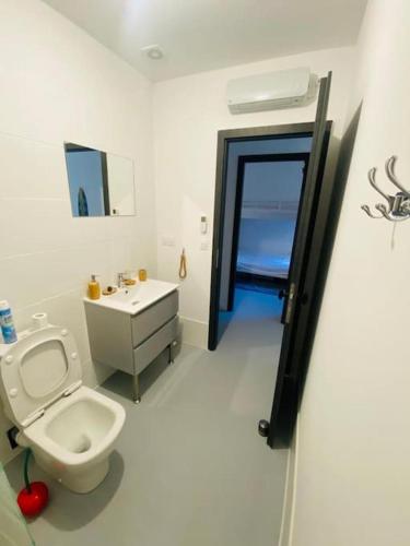 une salle de bain blanche avec des toilettes et un lavabo dans l'établissement Patio farniente, appartement entre mer et vigne, à Perpignan
