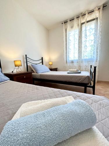 a bedroom with two beds and a window at Il tramonto tra Alghero e Stintino in Palmadula