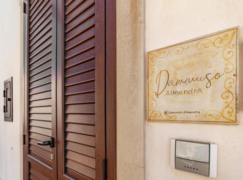 a door with a sign on the side of a building at Dammuso Almendra in Scicli